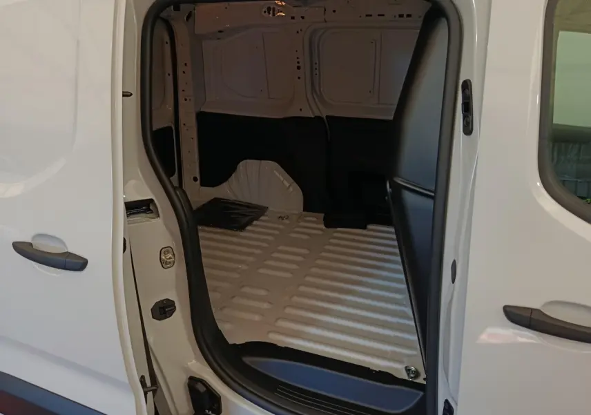 Vue intérieure du coffre blanc du Peugeot Partner Taille M avec porte latérale ouverte, montrant l'espace de chargement vide.