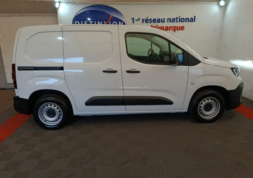 Vue de profil côté droit du Peugeot Partner blanc 2026 avec porte latérale coulissante et protections noires.