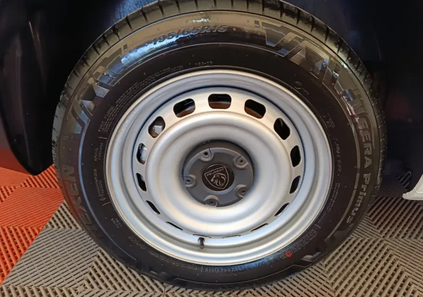Gros plan sur la roue acier grise avec logo Peugeot au centre du Peugeot Partner blanc 2026.