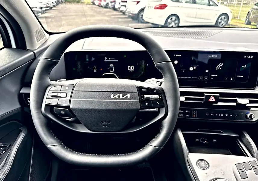 Vue intérieure centrée sur le volant cuir noir et le tableau de bord numérique du Kia Sportage blanc 2026 hybride.