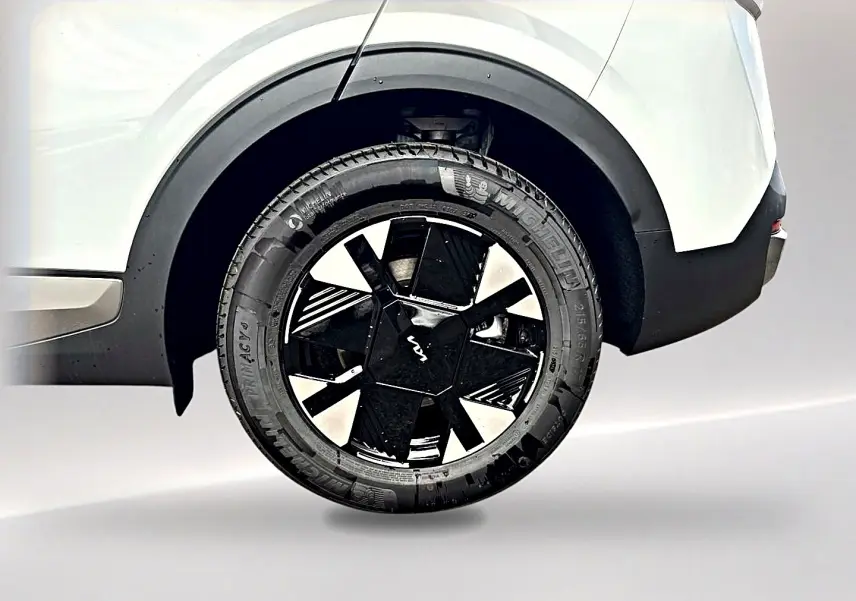Gros plan sur la roue arrière droite blanche du Kia Sportage 1.6 hybride 239 avec jante alu noire et détails modernes.