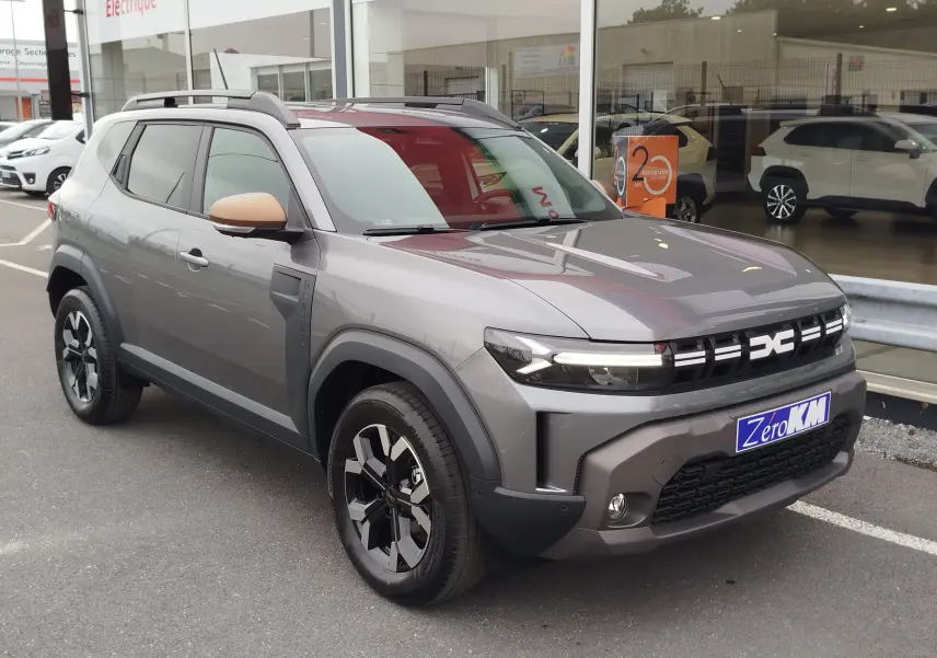 SUV Dacia Duster gris schiste en 3/4 avant droit, avec jantes noires et détails de calandre modernes visibles.