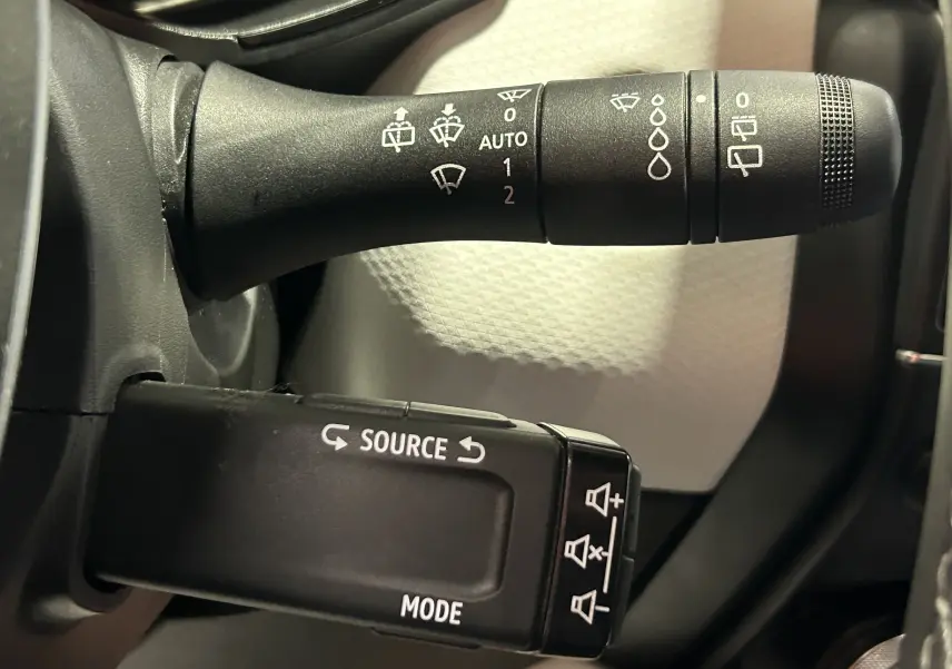 Gros plan sur les commandes au volant de la Renault Clio V TCe 90 Techno 2023, intérieur gris et noir.