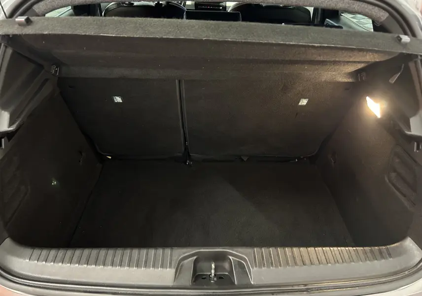 Coffre ouvert de la Renault Clio V TCe 90 TECHNO gris, vue intérieure arrière montrant l'espace de chargement vide et éclairé.