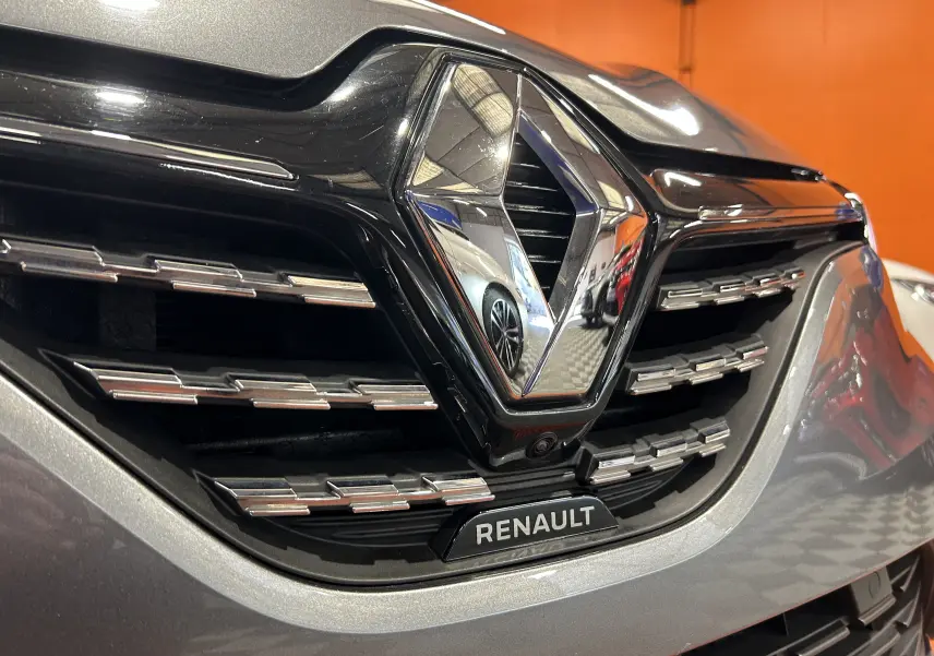 Gros plan sur la calandre avant grise d'une Renault Clio V 2023 avec logo chromé et caméra 360° intégrée.