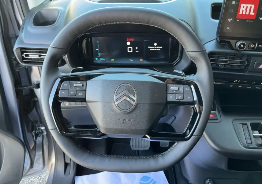 Vue rapprochée du volant cuir multifonctions du Citroën Berlingo 2025 avec tableau de bord digital et console centrale noire.