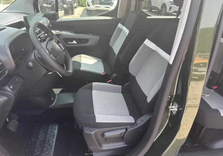 Vue intérieure côté conducteur du Citroën Berlingo 2025 Sirkka green, sièges tissu gris et noir avec volant cuir multifonctions.