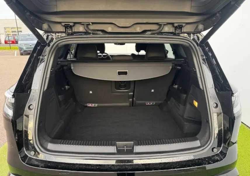 Coffre ouvert vu de l'arrière d'un Renault Espace VI noir étoilé, montrant un espace de chargement spacieux et propre.