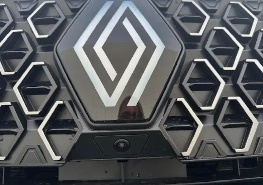 Gros plan sur la calandre noire étoilée du Renault Espace VI avec logo central et caméra avant intégrée.