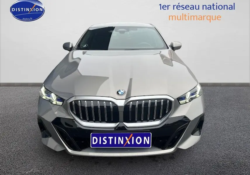 Vue avant d'une BMW Série 5 gris métallisé avec calandre imposante et phares LED allumés.