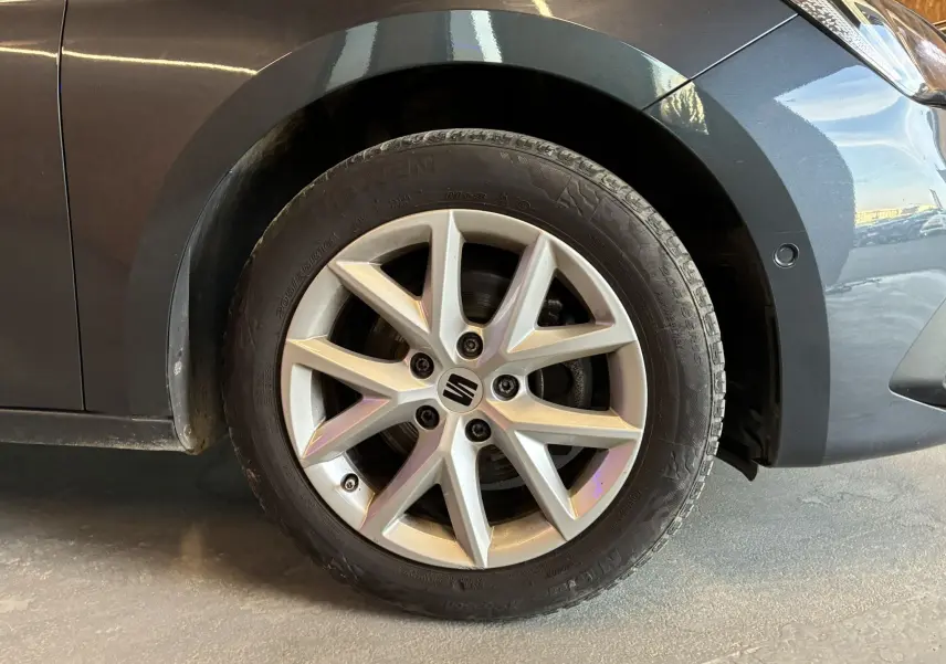 Gros plan sur la roue avant droite d'une SEAT Leon gris métallisé, mettant en valeur la jante alliage à 5 branches doubles.