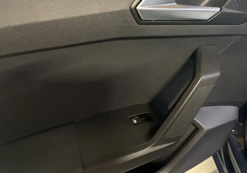 Détail de la porte intérieure côté conducteur d'une SEAT Leon gris 2021, avec bouton de verrouillage centralisé.