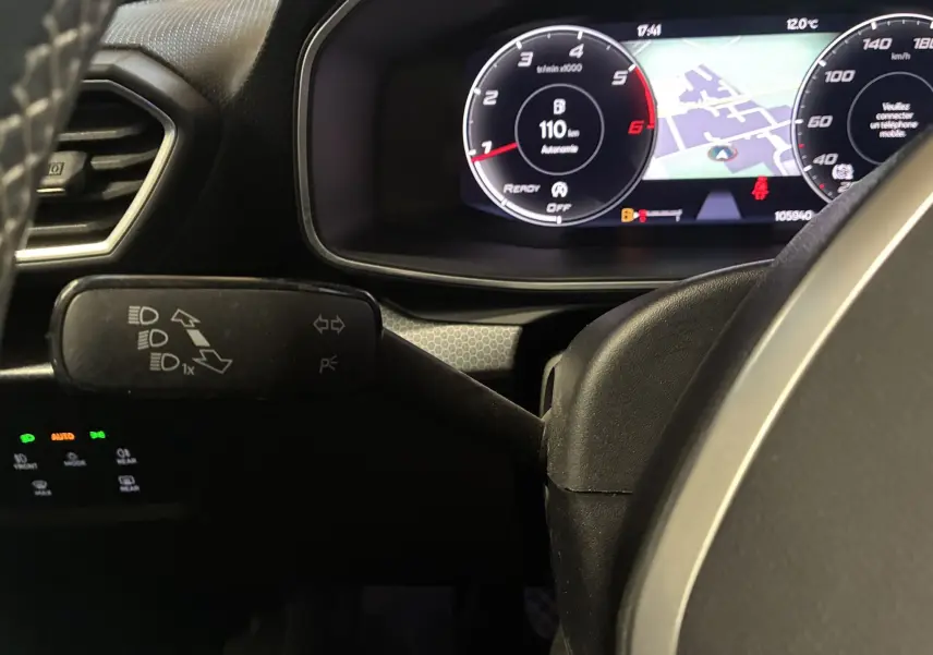 Gros plan sur le combiné d'instruments digital et le commodo gauche du volant dans l'habitacle noir du SEAT Leon gris 2021.