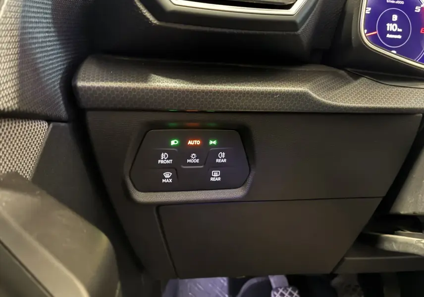 Détail du tableau de bord côté gauche du SEAT Leon gris 2021, avec commandes d’éclairage et affichage digital partiel.