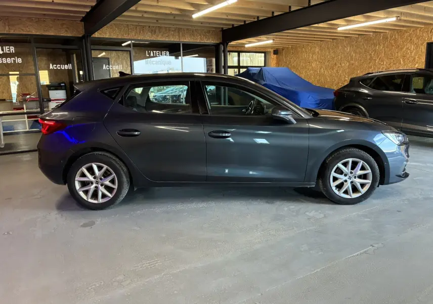 Vue latérale droite d'une SEAT Leon gris 2021 à cinq portes, garée en intérieur avec jantes alliage visibles.
