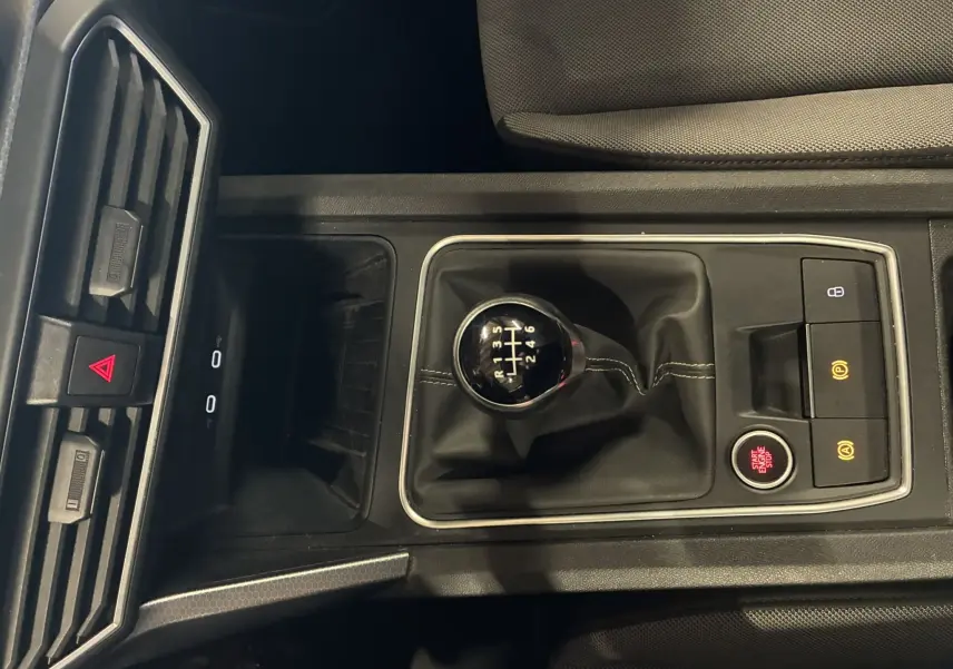 Vue rapprochée de la console centrale gris foncé du SEAT LEON 2.0 TDI 115 STYLE avec levier de vitesse manuel et boutons de contrôle.