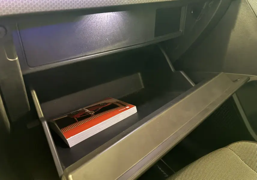 Gros plan sur la boîte à gants ouverte côté passager d'une SEAT Leon gris 2021 avec un manuel à l'intérieur.