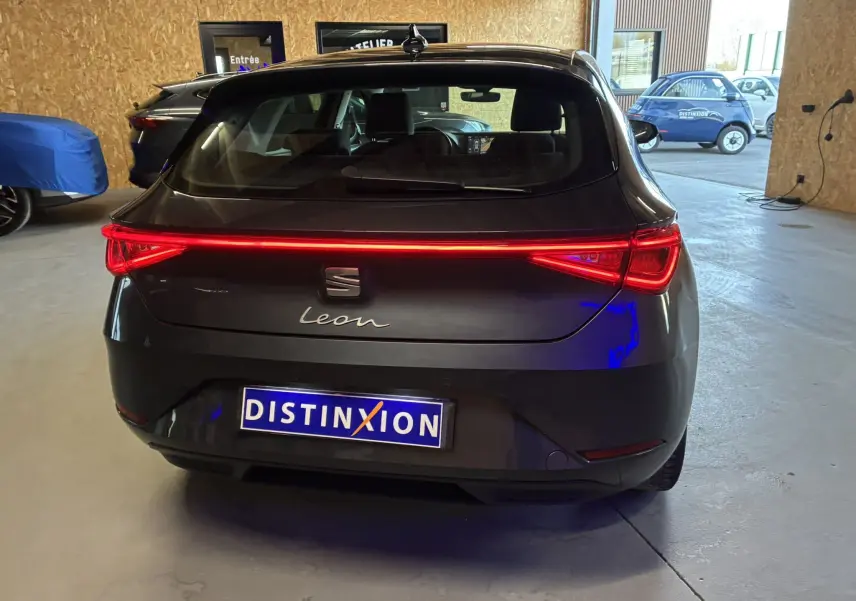 Vue arrière d'une SEAT Leon gris foncé avec feux arrière allumés, en intérieur dans un garage lumineux.
