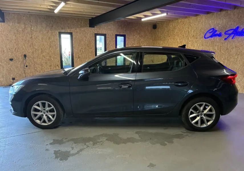 Vue latérale droite d'une SEAT Leon gris 2021, cinq portes, avec jantes alliage et intérieur visible noir.