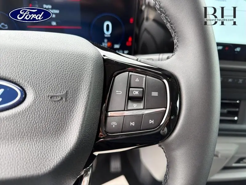 Gros plan sur les commandes multifonctions à droite du volant gris du Ford Transit Custom Fourgon 2026.