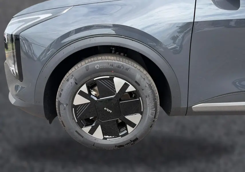 Gros plan sur la roue avant gauche du KIA SPORTAGE gris eclipse, avec jante alu noire et argentée au design moderne.