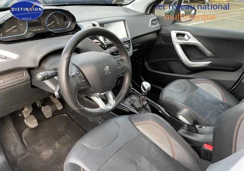 Intérieur de la Peugeot 2008 blanc vue côté conducteur, volant cuir perforé et levier de vitesse manuel visibles.