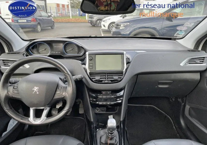 Vue intérieure frontale du tableau de bord noir du Peugeot 2008 blanc avec volant multifonction et écran central tactile.