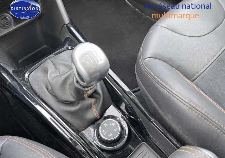 Gros plan sur la console centrale noire du Peugeot 2008 blanc de 2016, avec levier de vitesse manuel et siège cuir noir.