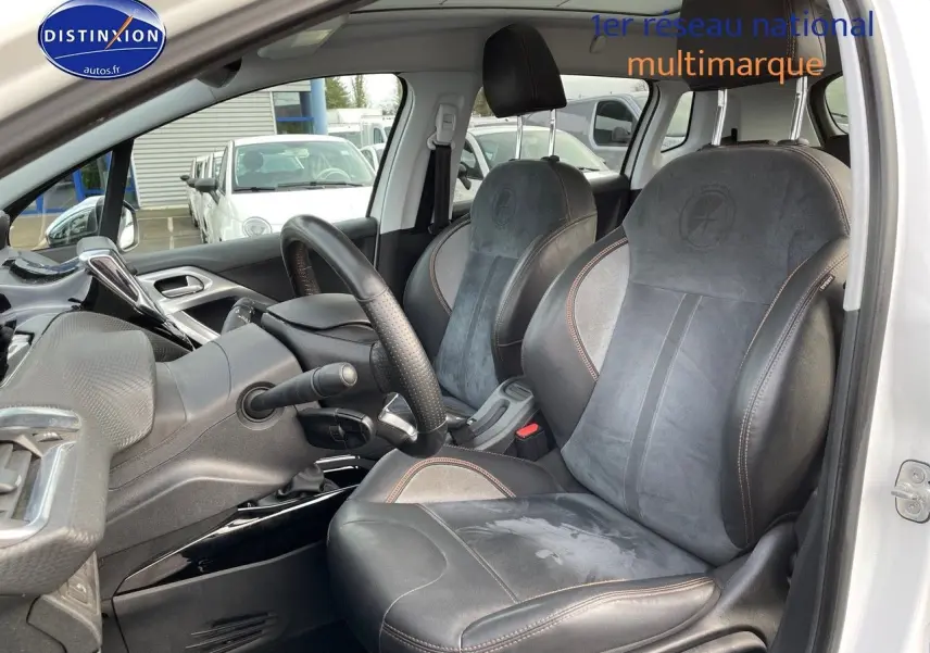 Intérieur du Peugeot 2008 blanc vu côté conducteur, mettant en valeur les sièges en cuir noir avec surpiqûres marron.