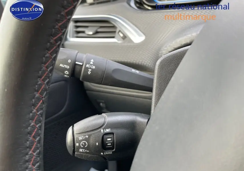 Vue rapprochée du volant côté gauche d'un Peugeot 2008 blanc, mettant en valeur les commandes de régulateur de vitesse.