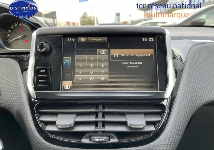 Écran tactile central du tableau de bord d'une Peugeot 2008 blanc, avec commandes et affichage radio visible.