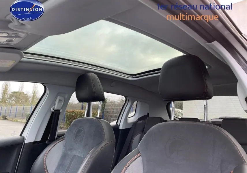 Vue intérieure du Peugeot 2008 blanc 2016, mettant en valeur les sièges avant en cuir noir avec surpiqûres contrastées et toit panoramique.