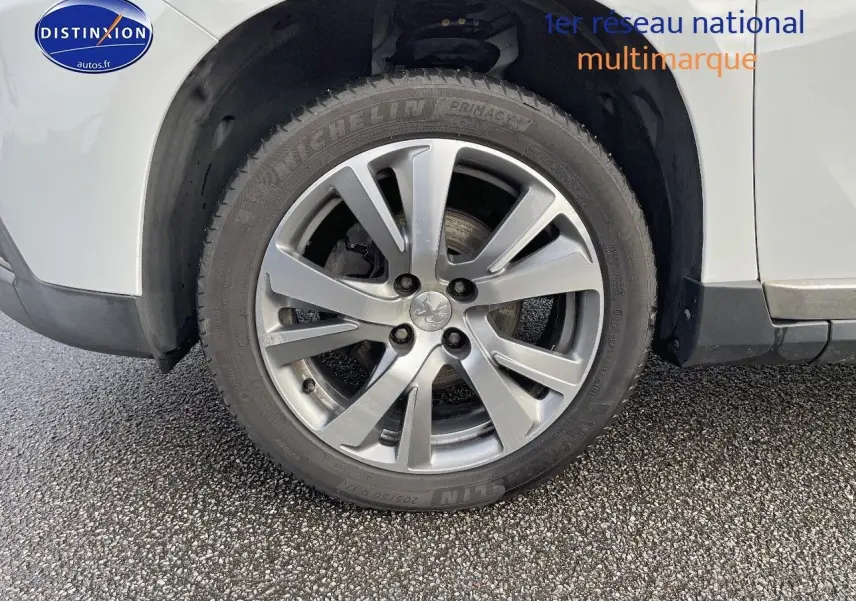 Gros plan sur la roue avant gauche en alliage argenté d'un Peugeot 2008 blanc de 2016.