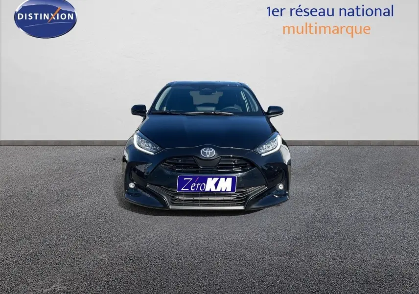 Vue frontale d'une Toyota Yaris Hybrid 116ch noir métal avec calandre imposante et phares LED allumés.