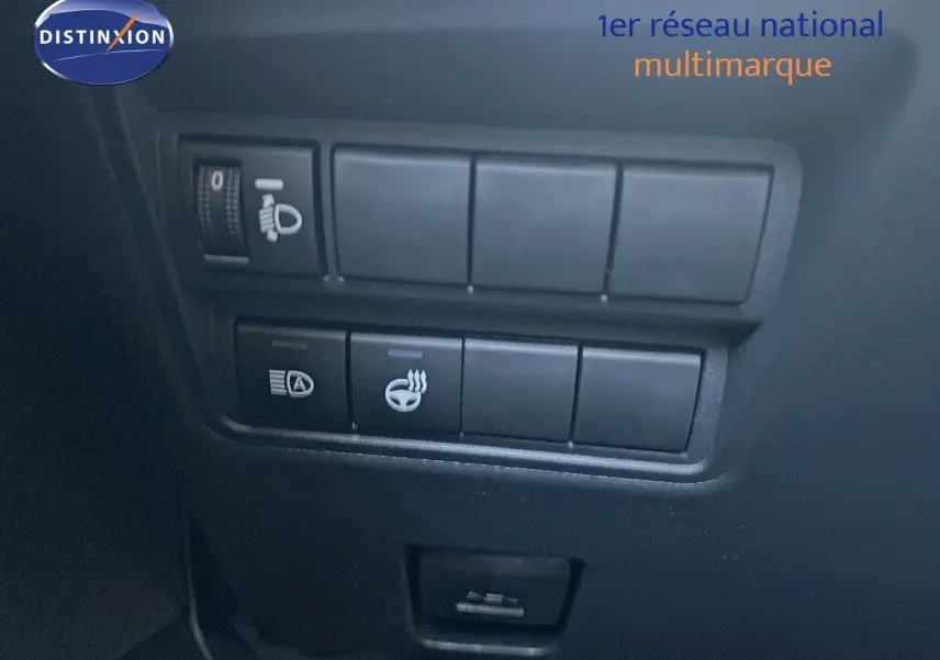 Gros plan sur les commandes de réglage des phares et du volant chauffant dans une Toyota Yaris Hybrid noire 2025.