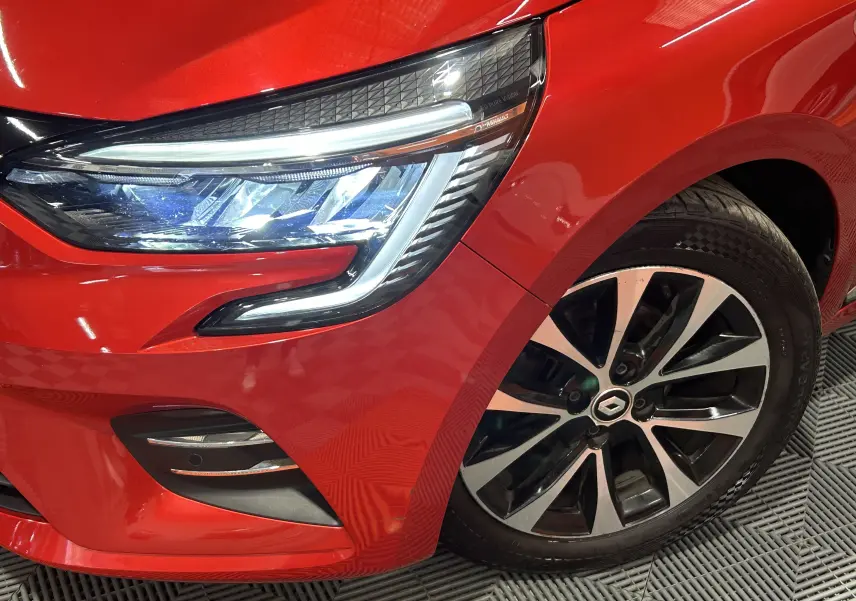 Gros plan sur l'avant droit rouge d'une Renault Clio V TCe 90 TECHNO avec phare LED et jante alliage noire et argent.