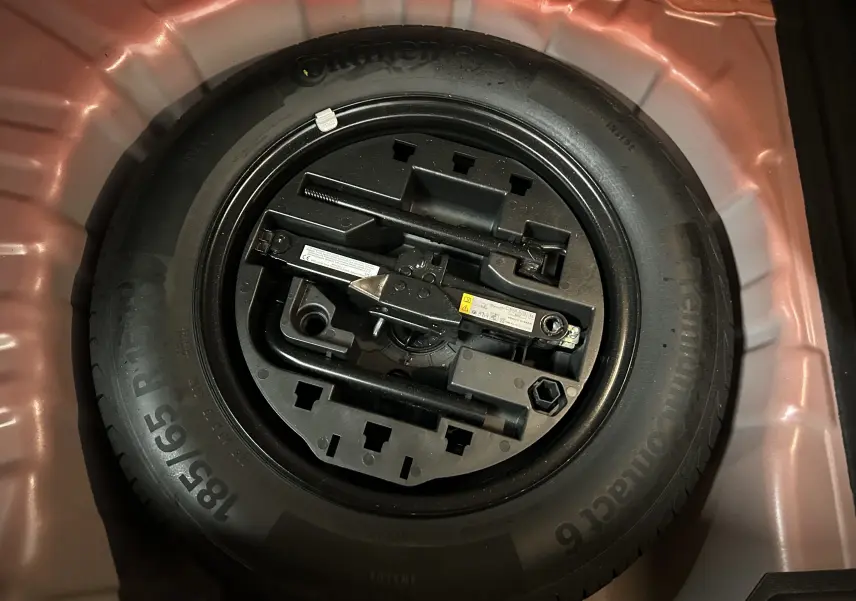 Roue de secours avec outils de changement rangés dans le coffre d'une Renault Clio V rouge 2023.