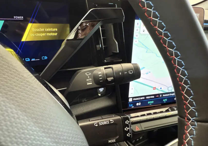 Gros plan sur la console centrale et volant cuir noir avec surpiqûres tricolores du Renault Espace gris foncé 2025 esprit Alpine.