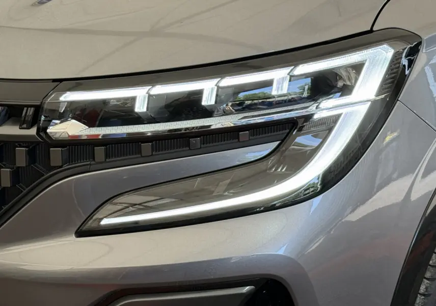 Gros plan sur le phare avant droit allumé du Renault Espace esprit Alpine gris foncé 2025 avec détails LED distinctifs.