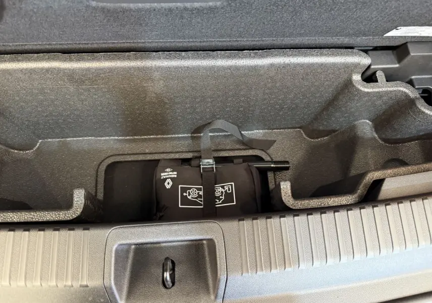 Rangement sous plancher de coffre avec kit de réparation pneus dans un Renault Espace gris foncé 2025.