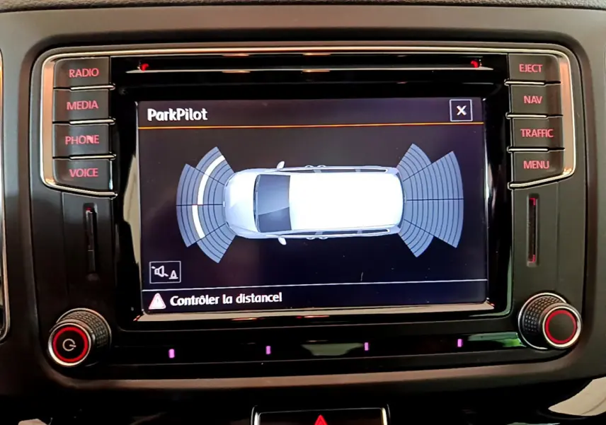 Écran tactile central du Volkswagen Sharan 2017 montrant l'aide au stationnement ParkPilot en vue de dessus du véhicule blanc.