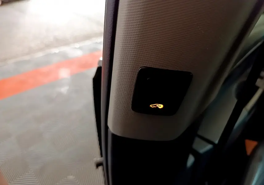 Bouton lumineux de fermeture électrique du hayon sur le montant intérieur d'une Volkswagen Sharan marron, vue rapprochée côté porte ouverte.