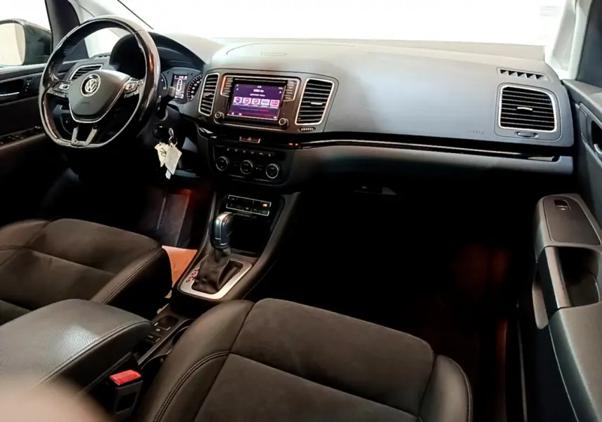 Vue intérieure avant droite du Volkswagen Sharan 2017 avec tableau de bord noir et écran tactile central.