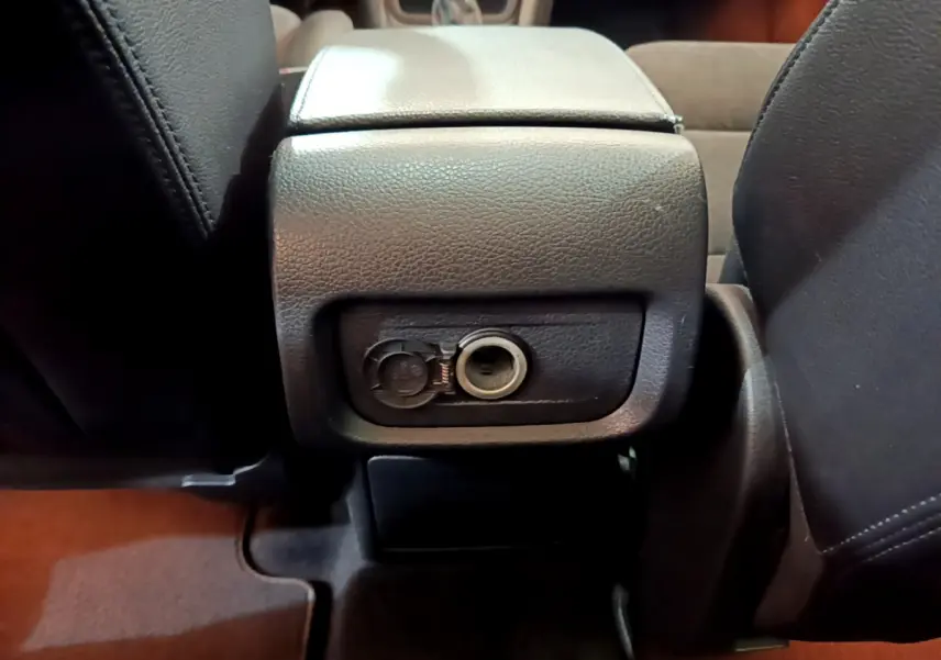 Prise 12V ouverte sous l'accoudoir central entre les sièges avant du Volkswagen Sharan marron 2017