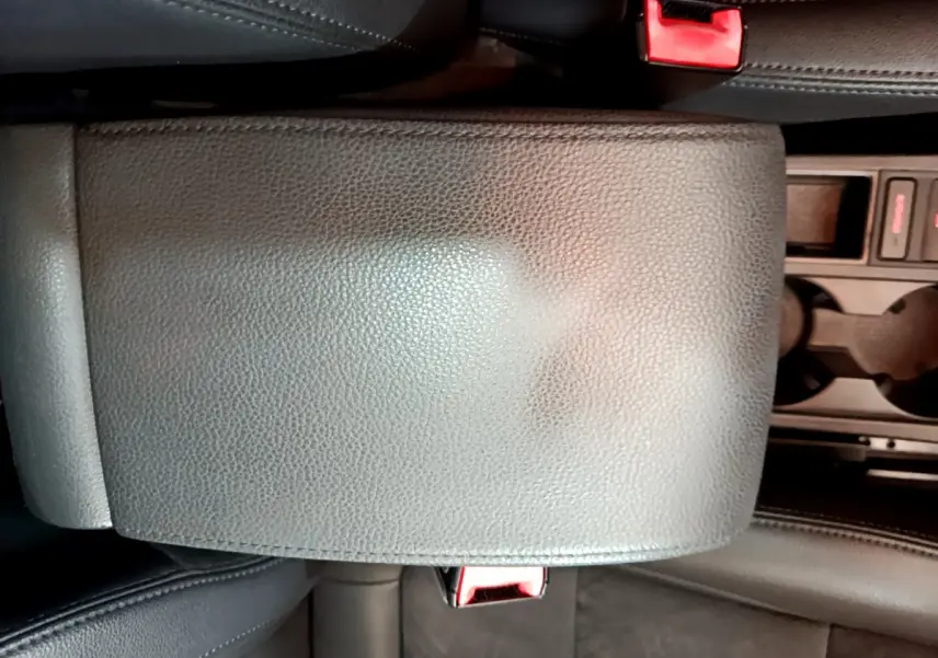Gros plan sur l'accoudoir central en cuir noir et la console avec porte-gobelets du Volkswagen Sharan marron 2017.