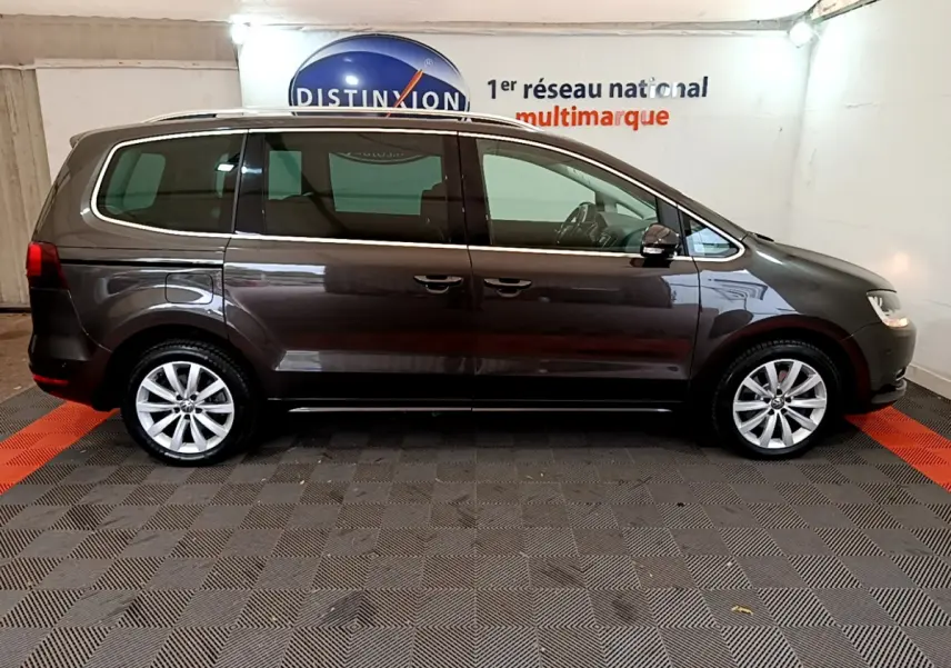 Profil latéral droit d'un Volkswagen Sharan marron 2017 dans un showroom avec sol en damier noir et rouge.