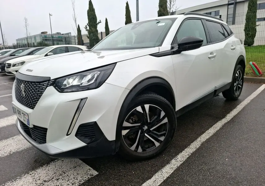 Peugeot 2008 blanc nacré vue 3/4 avant droit, avec jantes noires et détails noirs contrastants sur carrosserie.