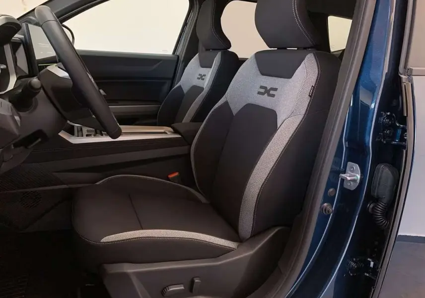 Vue intérieure côté conducteur du Dacia Bigster Hybrid 155 Journey Plus, sièges tissu noir et gris avec logo brodé.
