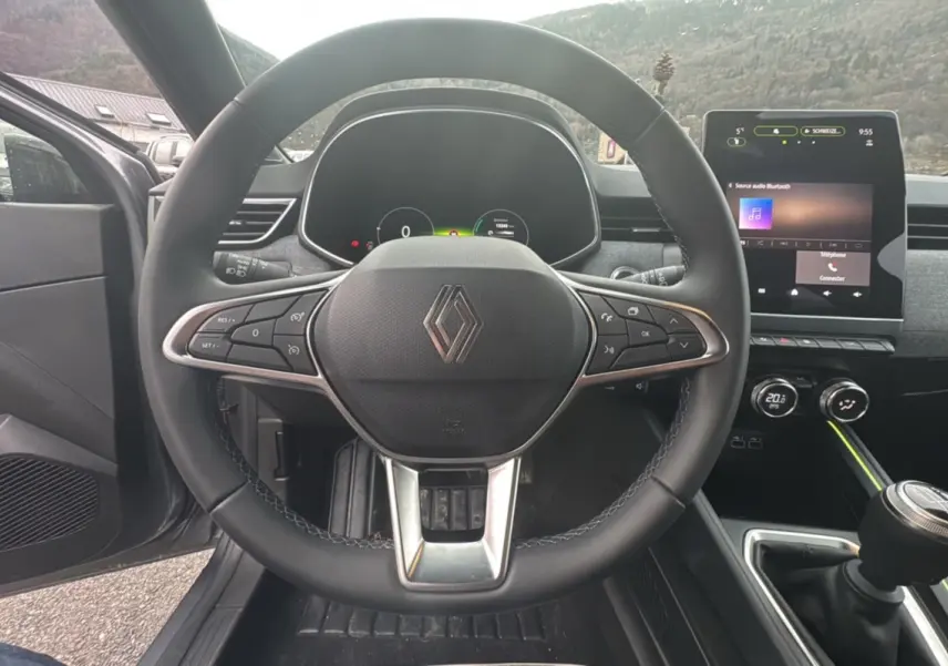 Vue intérieure centrée sur le volant cuir multifonctions et l’écran tactile 9,3 pouces de la Renault Clio gris schiste.