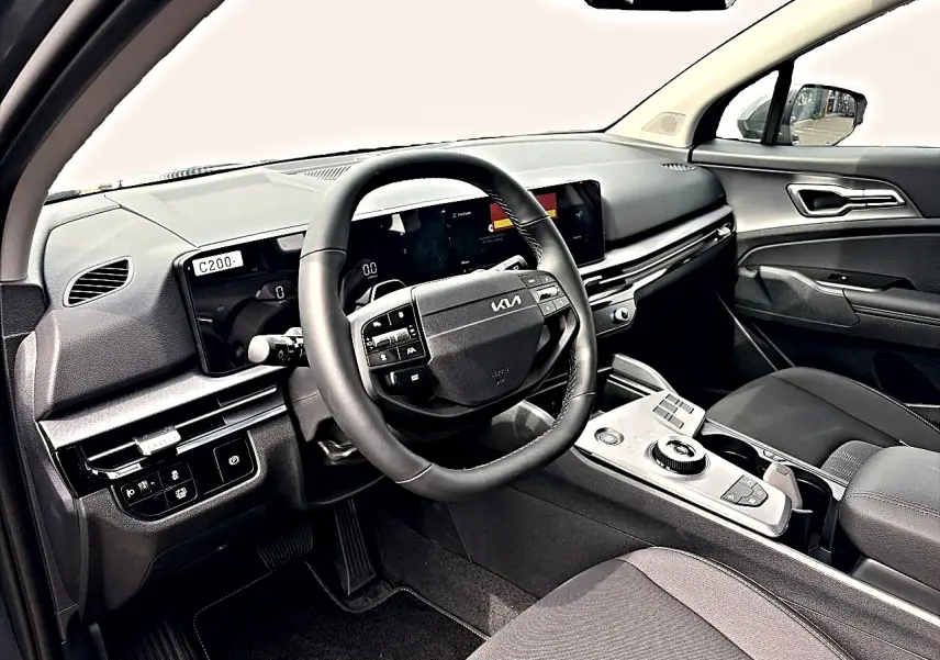Vue intérieure côté conducteur du tableau de bord et volant cuir noir du Kia Sportage 1.6 hybride 2026.